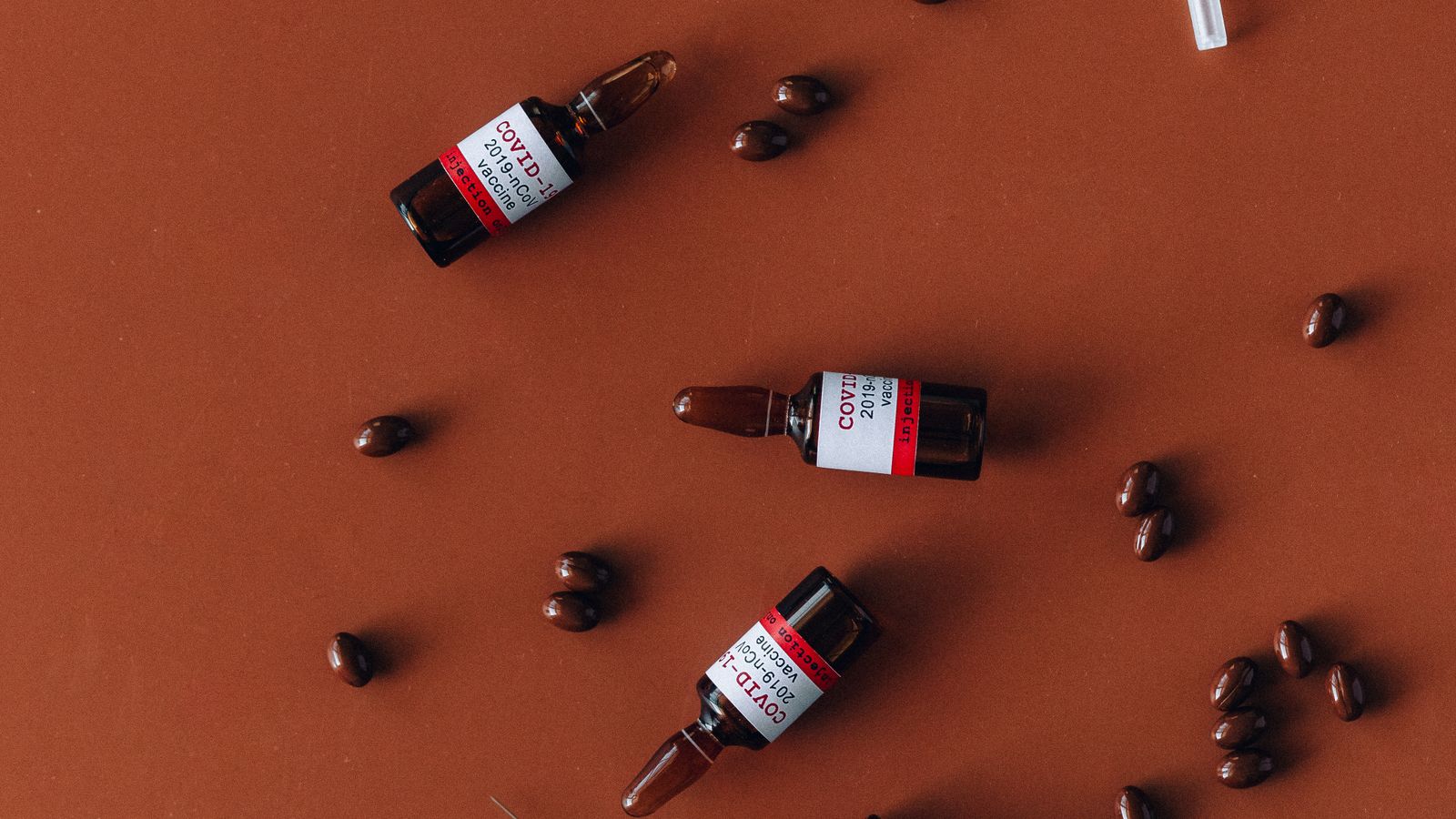 Medical vials and syringes scattered across a brown surface.